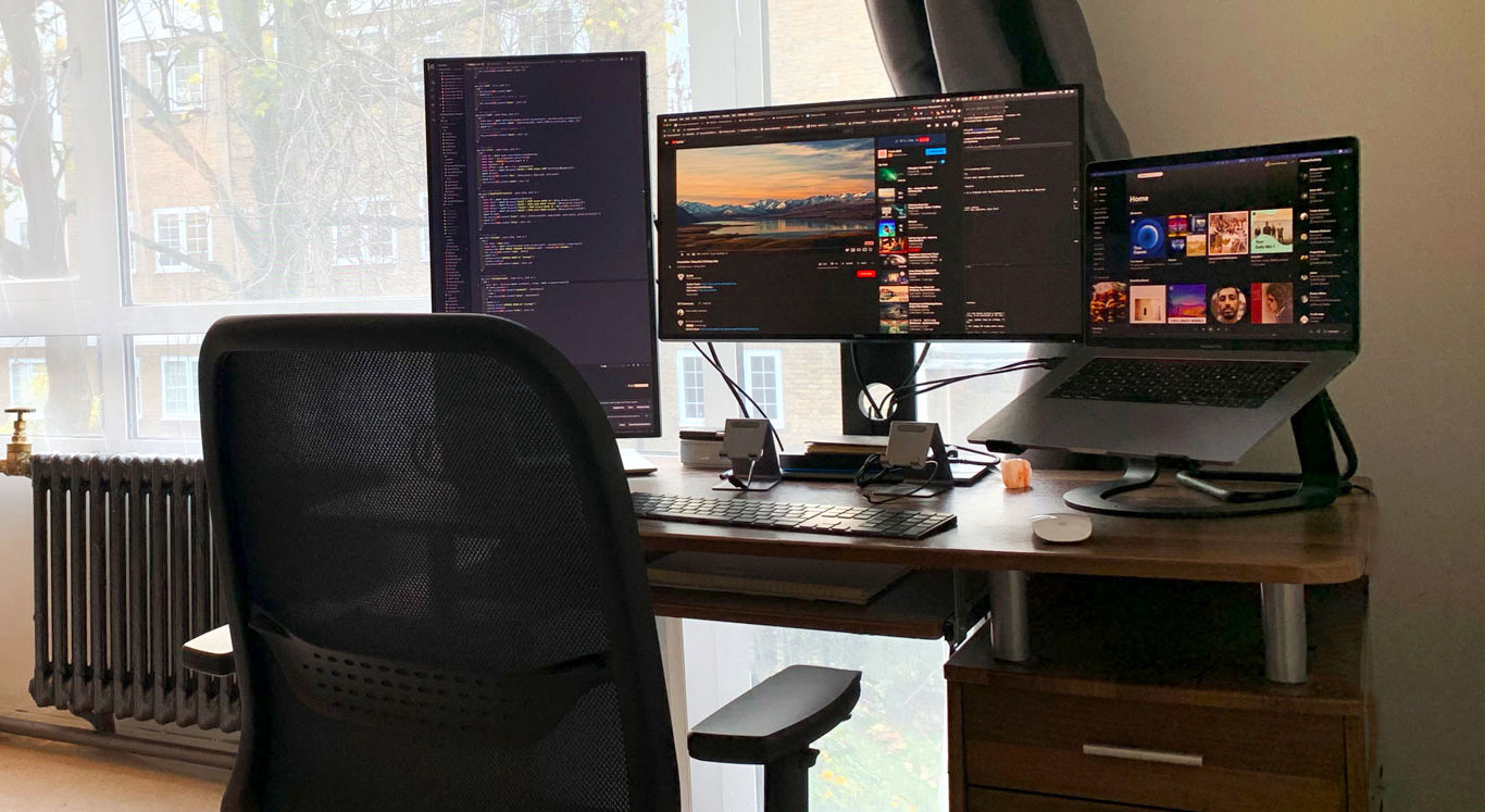 A desk with a MacBook Pro laptop and two Dell 4K monitors